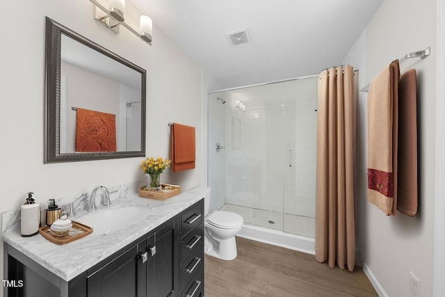 bathroom with wood finished floors, a stall shower, toilet, and vanity
