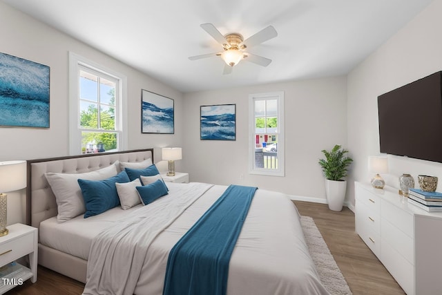 bedroom with light wood finished floors, a ceiling fan, and baseboards