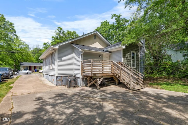 view of front of home featuring a deck, central AC unit, and concrete driveway