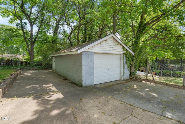 detached garage featuring driveway and fence