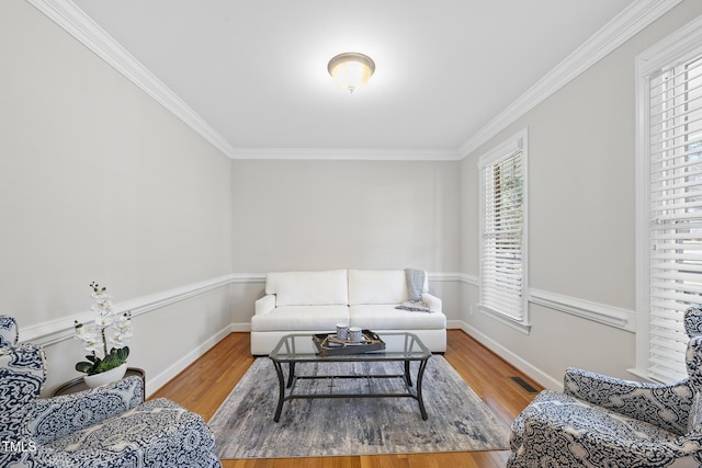 living area featuring crown molding, visible vents, baseboards, and wood finished floors