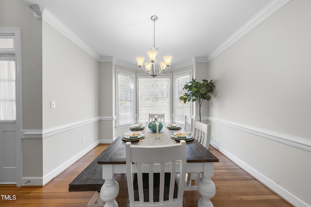 dining space featuring baseboards, a chandelier, wood finished floors, and ornamental molding