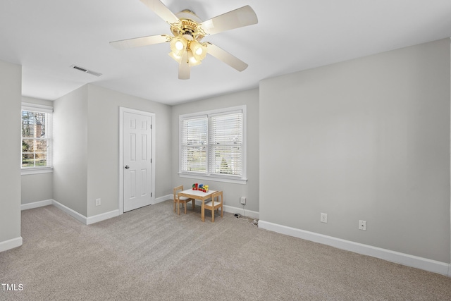 interior space featuring a ceiling fan, light colored carpet, visible vents, and baseboards