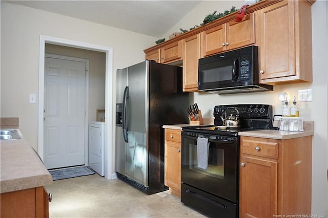 kitchen featuring black appliances, lofted ceiling, and washer / dryer