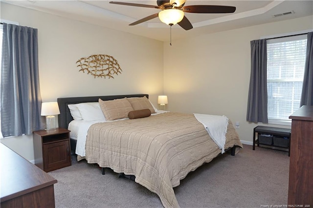 carpeted bedroom featuring multiple windows and ceiling fan