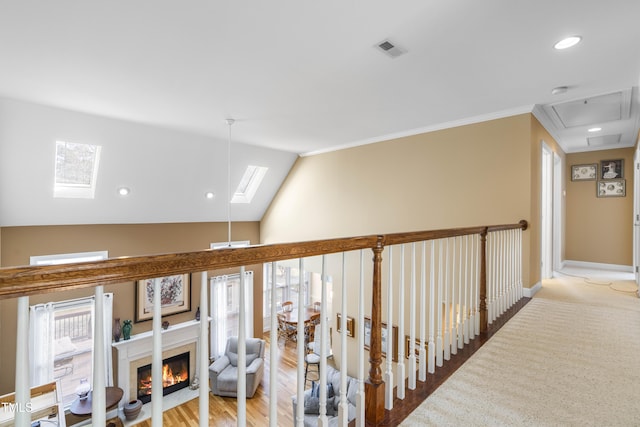 corridor with ornamental molding, hardwood / wood-style floors, and lofted ceiling with skylight