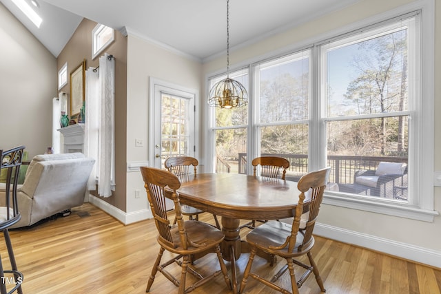 dining room featuring crown molding, light wood-type flooring, vaulted ceiling, and a notable chandelier