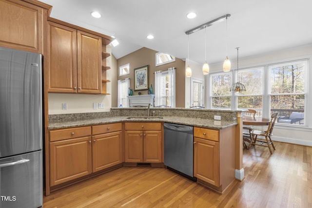 kitchen featuring appliances with stainless steel finishes, decorative light fixtures, dark stone counters, sink, and kitchen peninsula