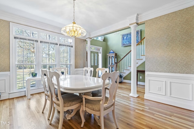 dining area with ornate columns, light hardwood / wood-style flooring, ornamental molding, and a chandelier