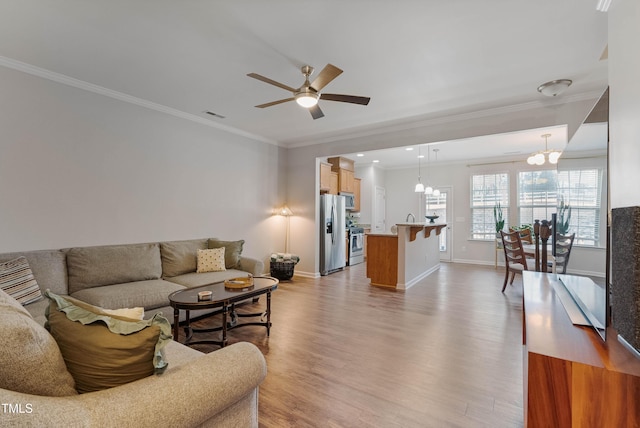 living room featuring ceiling fan with notable chandelier, ornamental molding, and light hardwood / wood-style floors