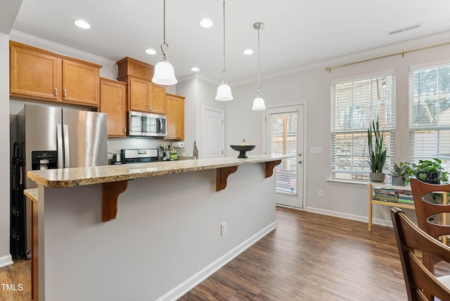 kitchen with a kitchen bar, crown molding, hanging light fixtures, an island with sink, and stainless steel appliances