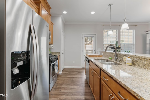 kitchen with stainless steel appliances, decorative light fixtures, crown molding, light stone counters, and sink