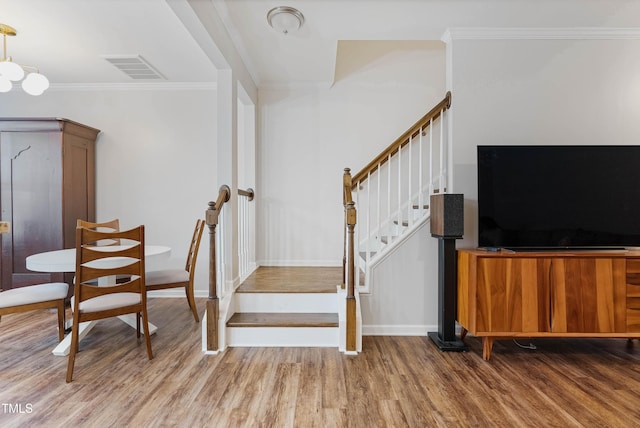 stairs with wood-type flooring and crown molding