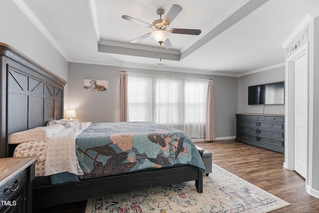 bedroom with ceiling fan, crown molding, a tray ceiling, and hardwood / wood-style floors