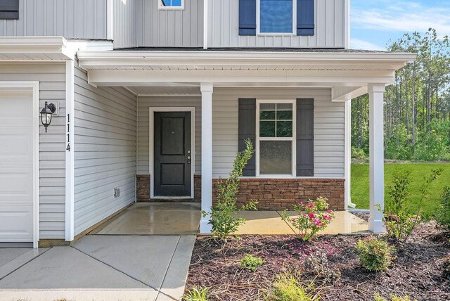 1114 Talmage Rd, Saint Pauls, NC 28384 - view of exterior entry with board and batten siding, a garage, a porch, and stone siding