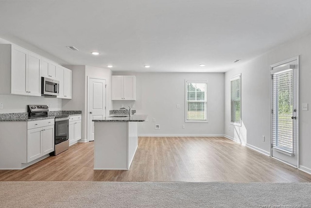 1114 Talmage Rd, Saint Pauls, NC 28384 - kitchen featuring appliances with stainless steel finishes, white cabinetry, a sink, light wood-type flooring, and dark stone counters