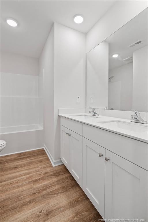 1114 Talmage Rd, Saint Pauls, NC 28384 - full bathroom with wood finished floors, double vanity, toilet, baseboards, and shower / bath combination