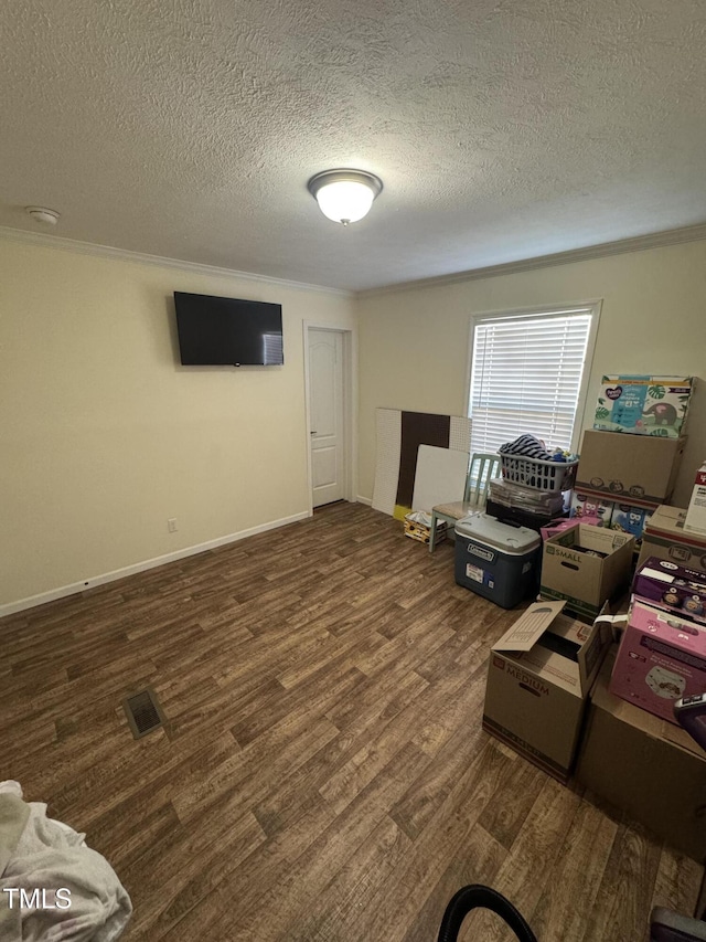 interior space with dark hardwood / wood-style flooring, ornamental molding, and a textured ceiling