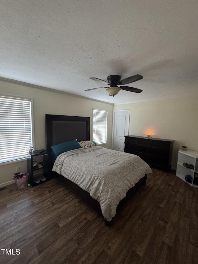 bedroom with ceiling fan, dark hardwood / wood-style floors, multiple windows, and a textured ceiling