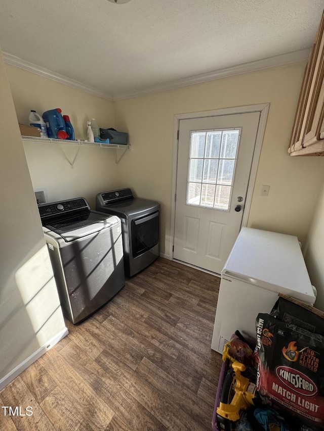 washroom with washing machine and dryer, dark wood-type flooring, ornamental molding, and cabinets