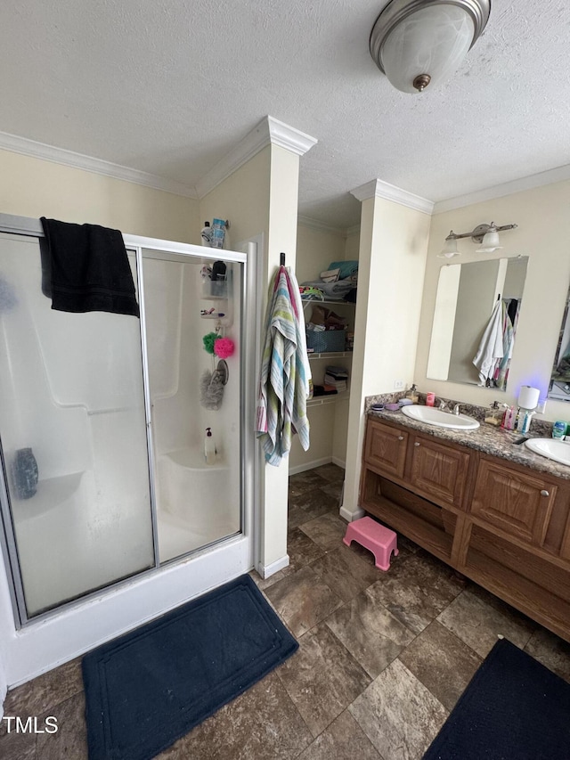 bathroom featuring a textured ceiling, crown molding, a shower with shower door, and vanity