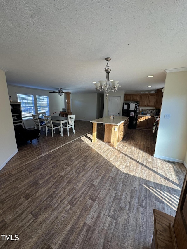 interior space with black fridge, pendant lighting, a kitchen island, dark wood-type flooring, and a breakfast bar area