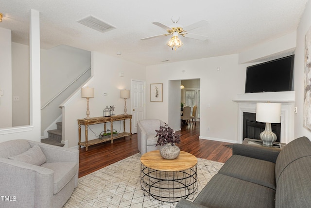 living room featuring a textured ceiling, light wood-type flooring, and ceiling fan