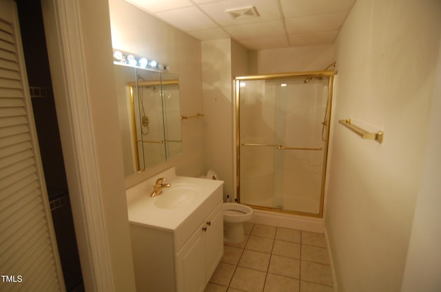 bathroom with a drop ceiling, toilet, tile patterned floors, an enclosed shower, and vanity