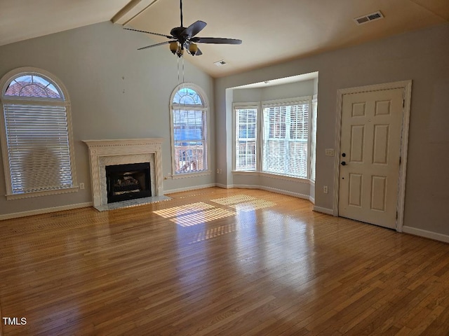 unfurnished living room with ceiling fan, a premium fireplace, light hardwood / wood-style flooring, and lofted ceiling with beams