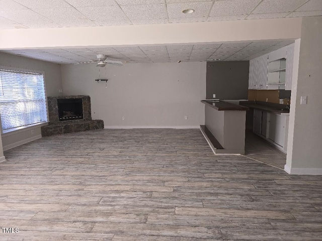 unfurnished living room with ceiling fan, hardwood / wood-style floors, and a fireplace