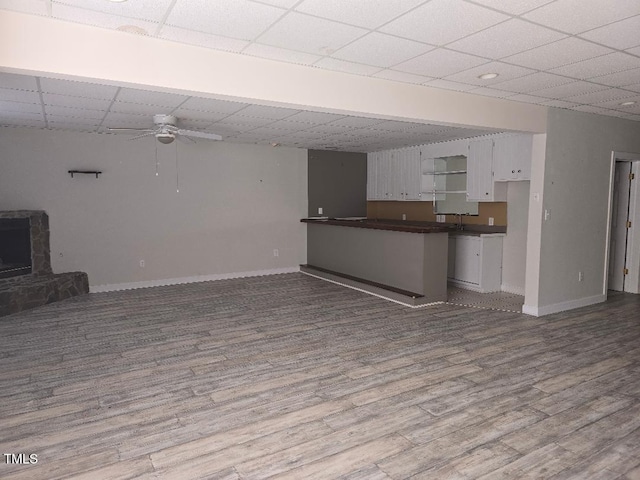 unfurnished living room with hardwood / wood-style flooring, a drop ceiling, and ceiling fan