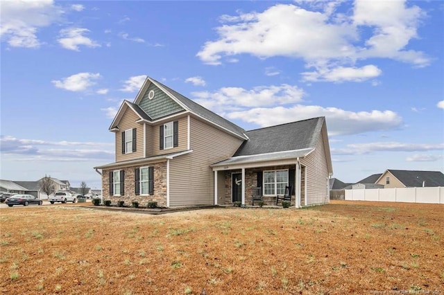 view of front of house featuring stone siding, a front yard, and fence