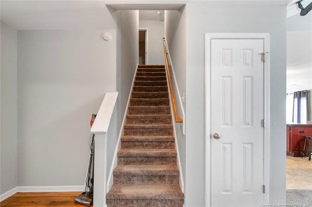 staircase featuring baseboards and wood finished floors