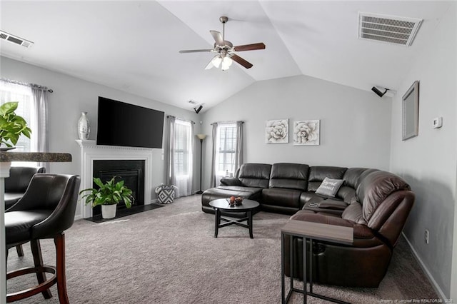 living room with lofted ceiling, a fireplace with flush hearth, visible vents, and carpet flooring