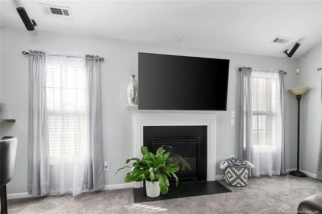 carpeted living room with a fireplace with flush hearth, visible vents, and baseboards