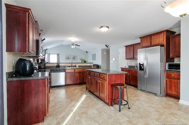 kitchen with appliances with stainless steel finishes, backsplash, dark countertops, and a sink