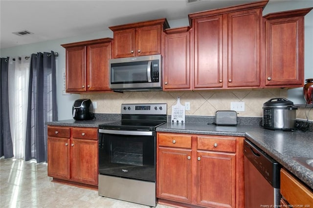 kitchen featuring stainless steel appliances, tasteful backsplash, dark countertops, and brown cabinets