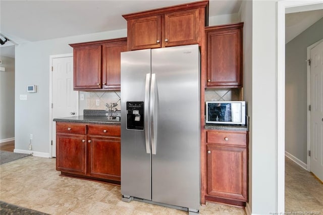 kitchen featuring backsplash, stainless steel fridge, and baseboards