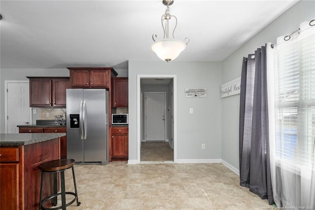 kitchen with baseboards, decorative backsplash, stainless steel fridge with ice dispenser, dark countertops, and pendant lighting