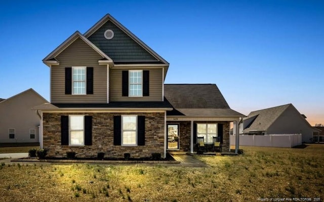 view of front of house featuring stone siding and a lawn