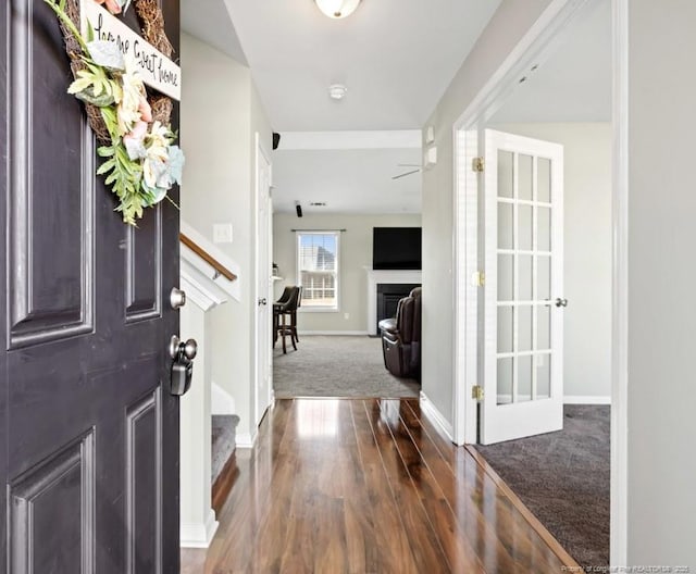 carpeted foyer with stairway, baseboards, and wood finished floors