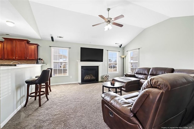 carpeted living room with visible vents, baseboards, a fireplace with flush hearth, lofted ceiling, and a ceiling fan