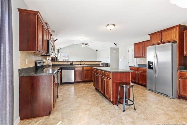 kitchen featuring ceiling fan, dark countertops, a center island, and stainless steel appliances