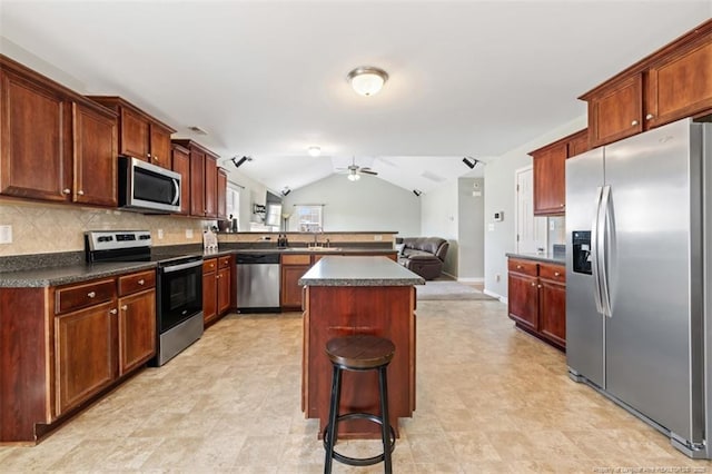 kitchen with dark countertops, open floor plan, appliances with stainless steel finishes, lofted ceiling, and ceiling fan