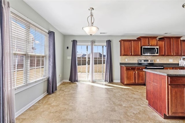 kitchen featuring dark countertops, baseboards, tasteful backsplash, and appliances with stainless steel finishes