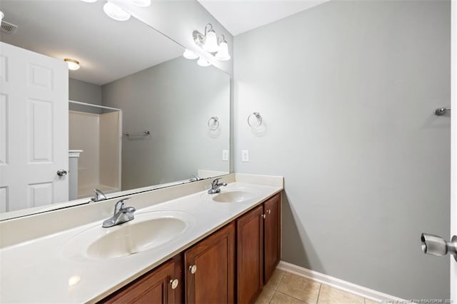 full bath featuring tile patterned flooring, double vanity, baseboards, and a sink