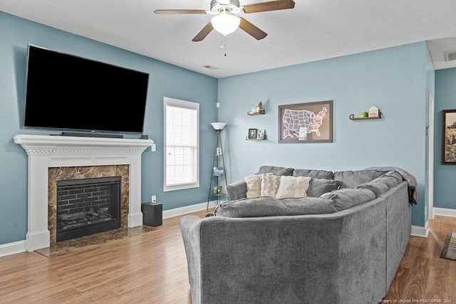 living room with ceiling fan, wood-type flooring, and a fireplace