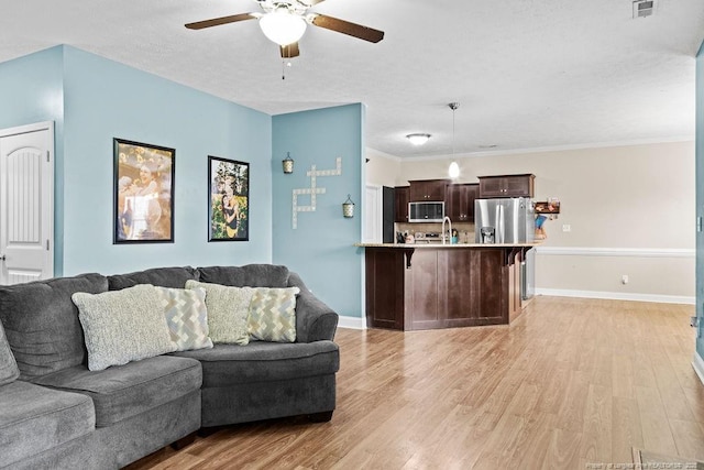 living room with ceiling fan, light hardwood / wood-style floors, ornamental molding, and sink