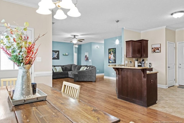 dining room featuring sink, ceiling fan with notable chandelier, and ornamental molding