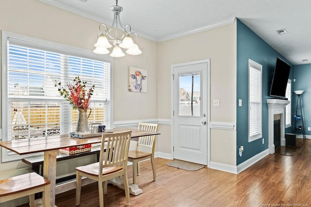 dining area with hardwood / wood-style floors, an inviting chandelier, a wealth of natural light, and ornamental molding